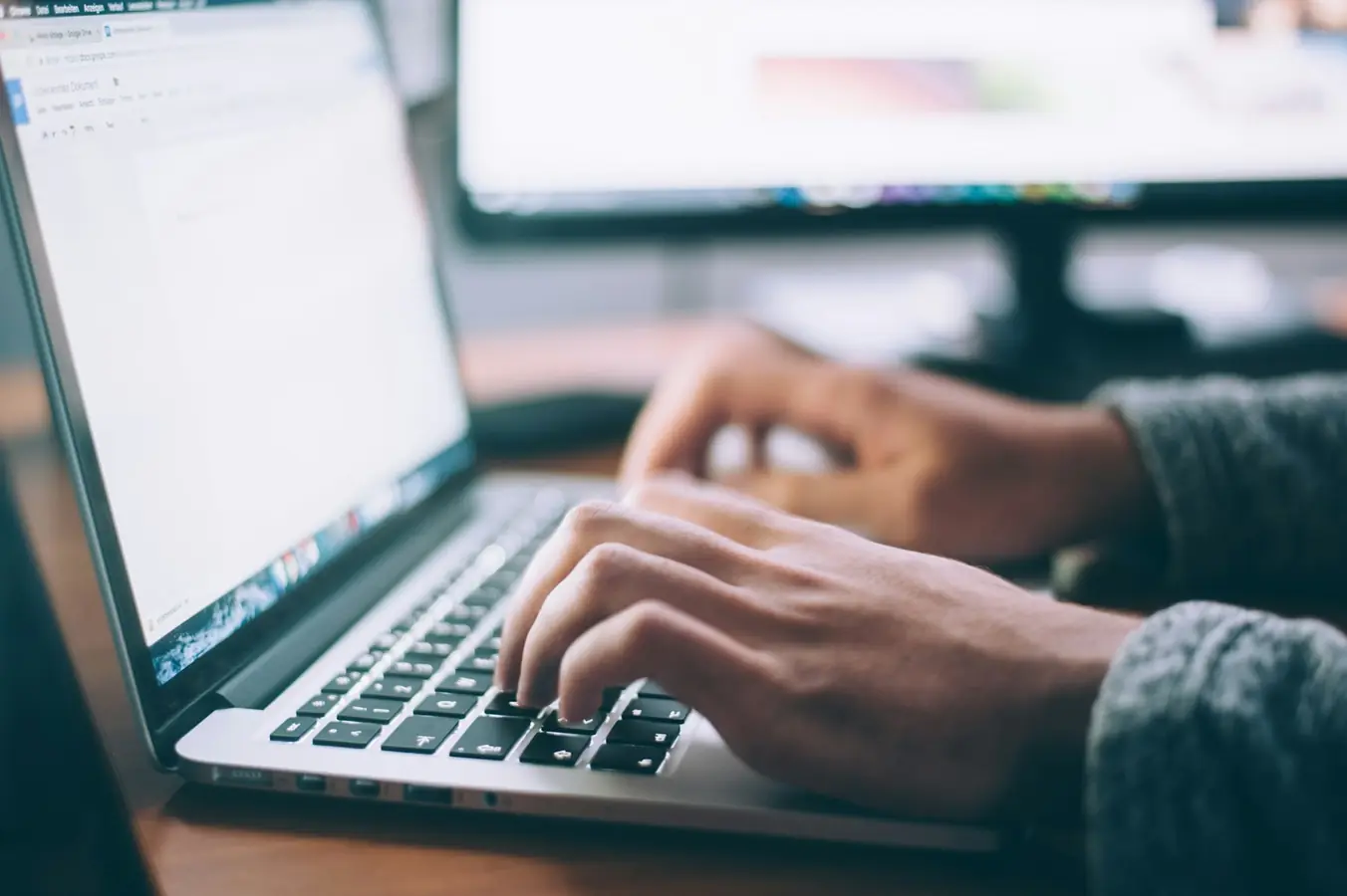Digital nomad working on a laptop at a bright desk, building an online app business while traveling