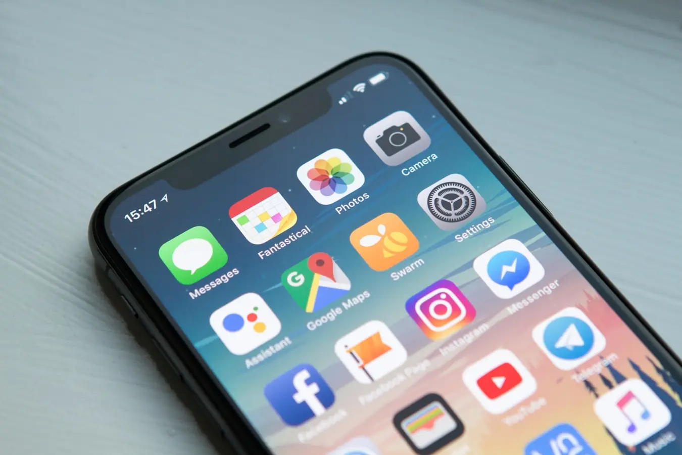 Person holding a smartphone with apps on the home screen, the kind of place a nomad side hustle app would live