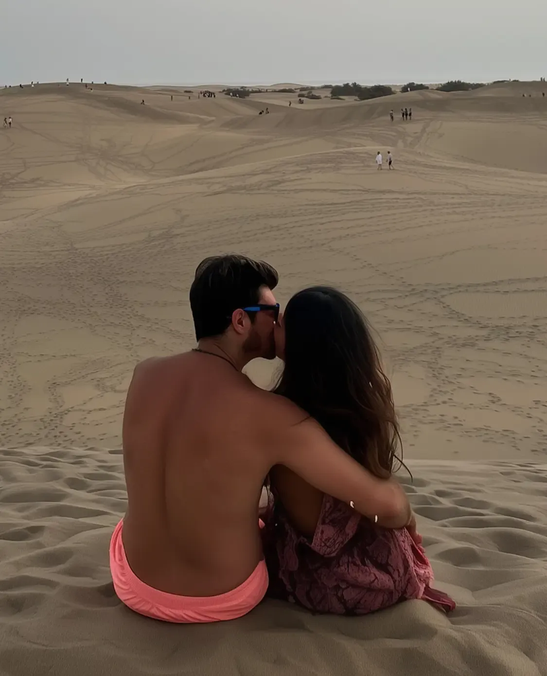 Digital nomad couple kissing on a sand dune while travelling together