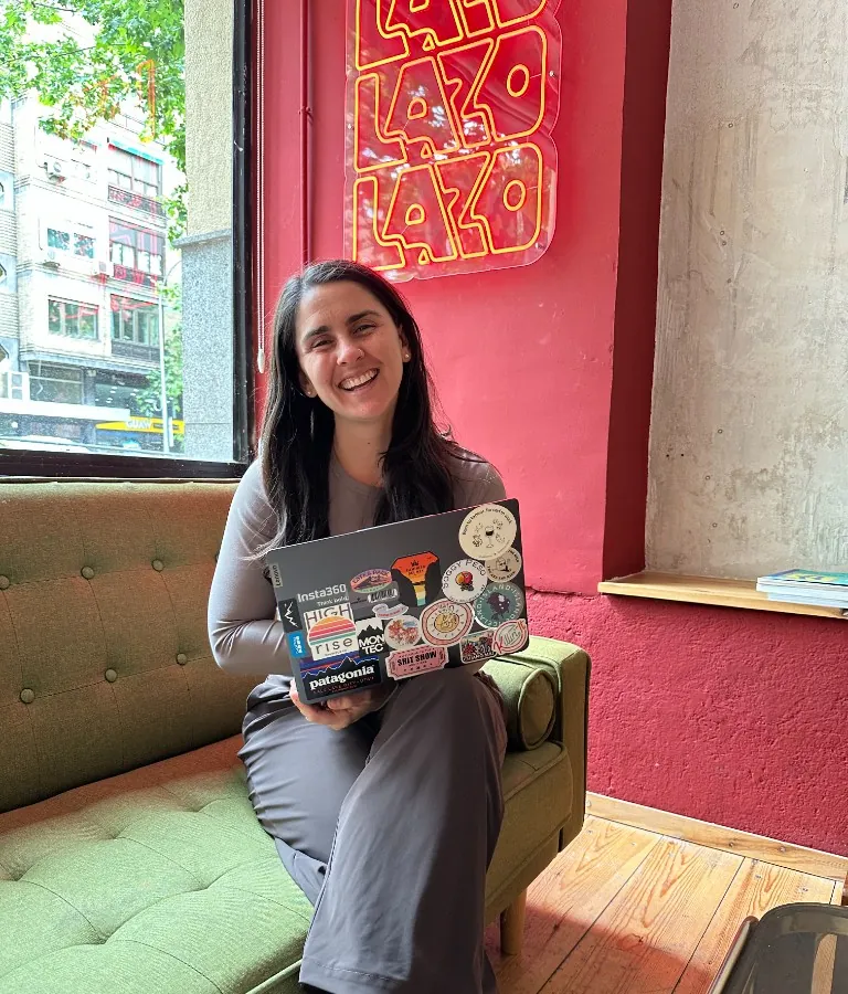 Salina Owens with a sticker-covered laptop on a green sofa at Lazo Madrid cafe