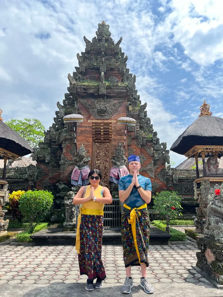 Nicole and her husband in traditional sash and sarong at a Balinese temple gate