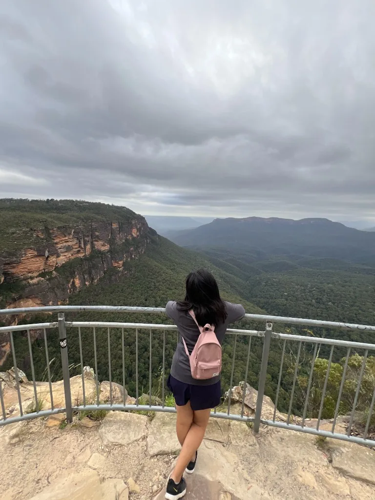 Nicole Moreno-Deinzer looking out over a forested canyon from a mountain viewpoint during solo travel