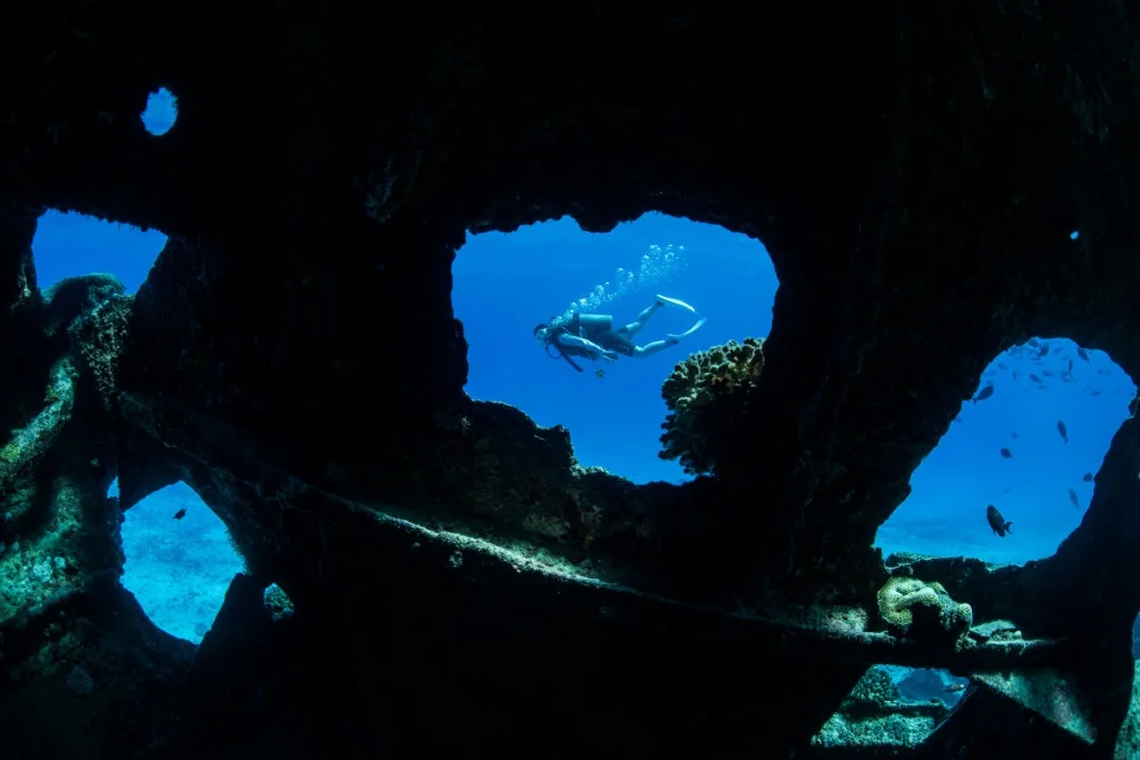 Scuba diver seen through a hatch from inside the Chinsen Shoan Maru shipwreck, Saipan